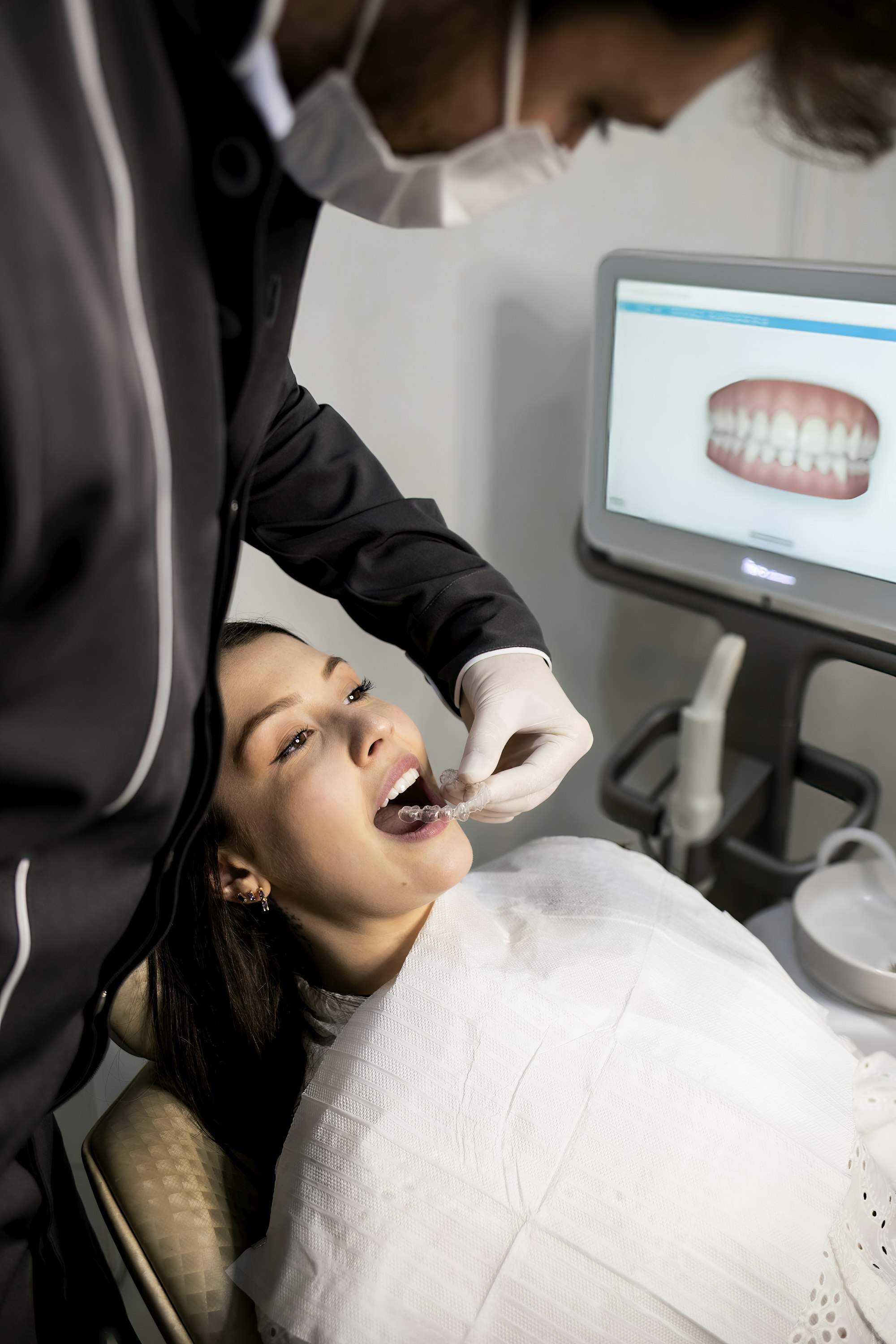 A clinician taking a digital intraoral scan while a 3D model of the patient's teeth appears on screen