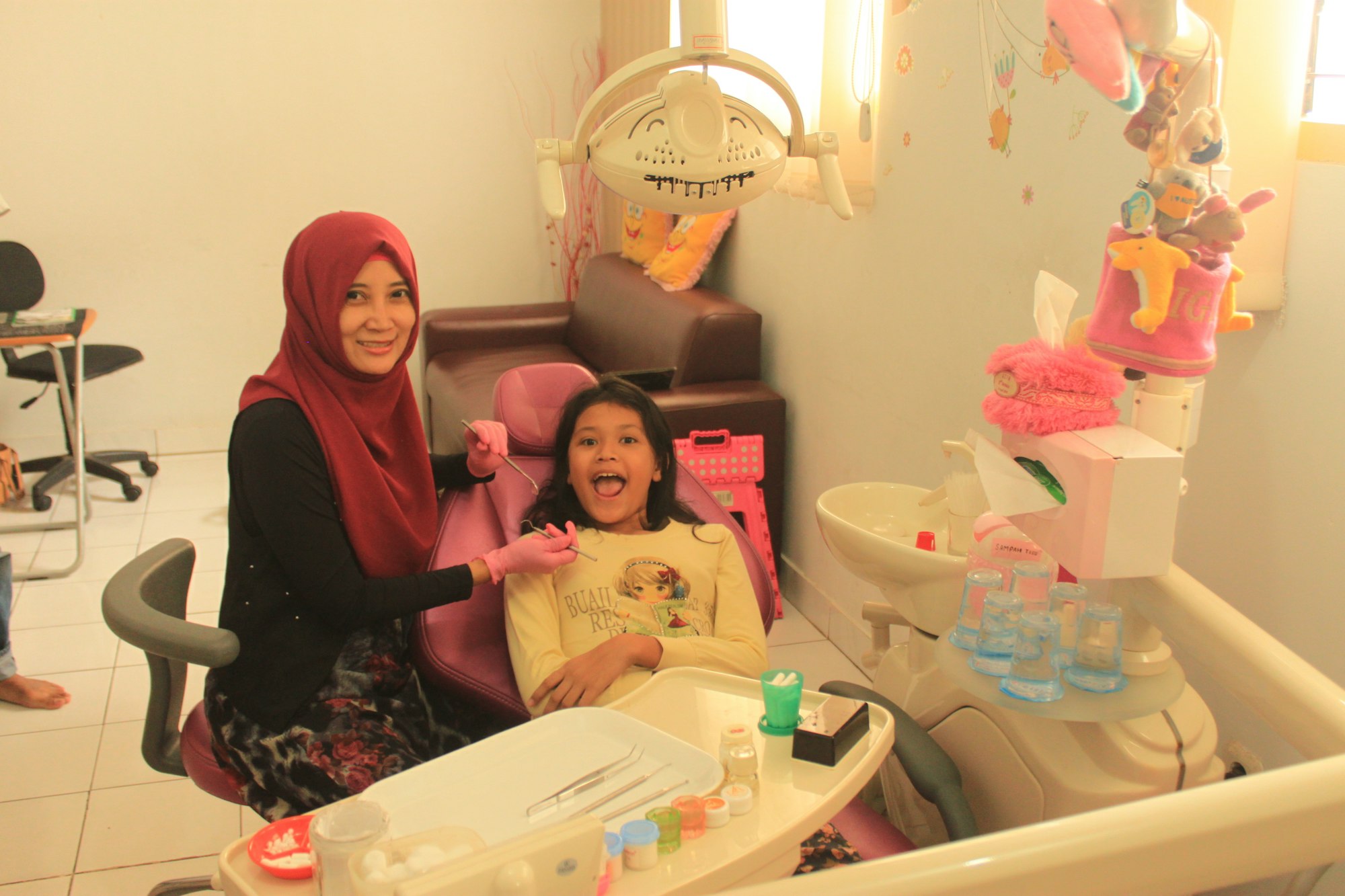 A parent and young child smiling together in a bright dental office