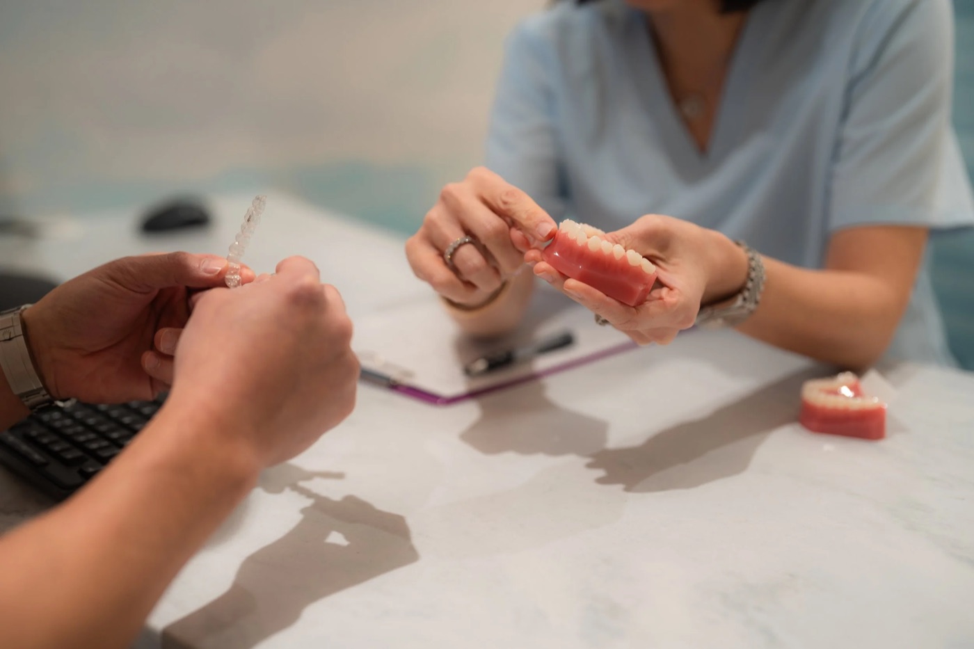 Two people reviewing a model of teeth across a consultation desk