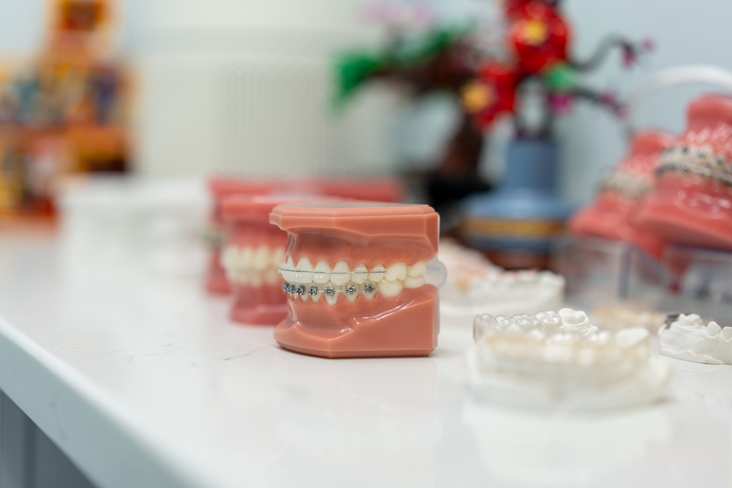 A dental model with braces beside clear aligners on the counter at our Brooklyn office