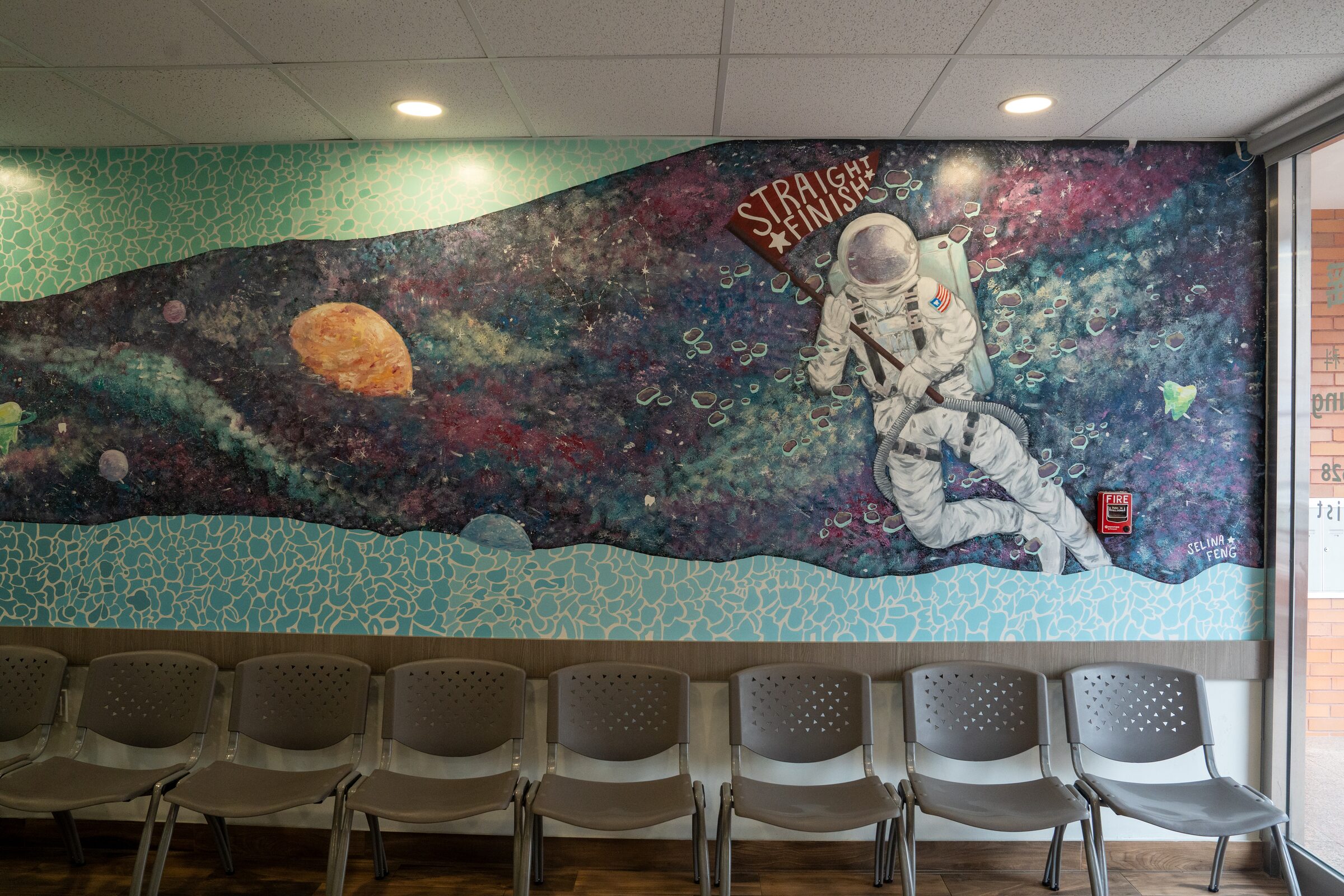 The waiting room, with a row of chairs beneath the astronaut mosaic mural