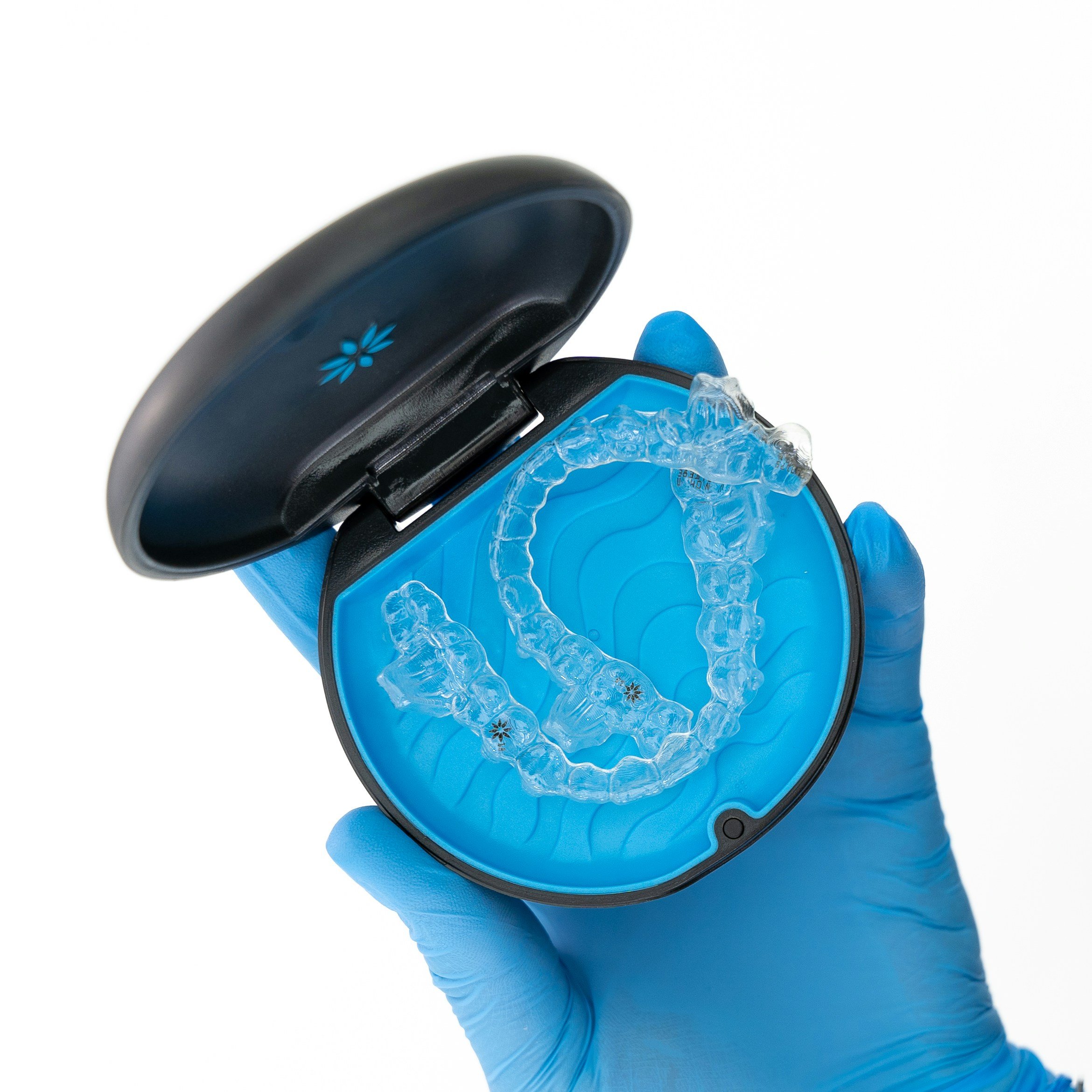 Gloved hand holding a clear aligner in its case