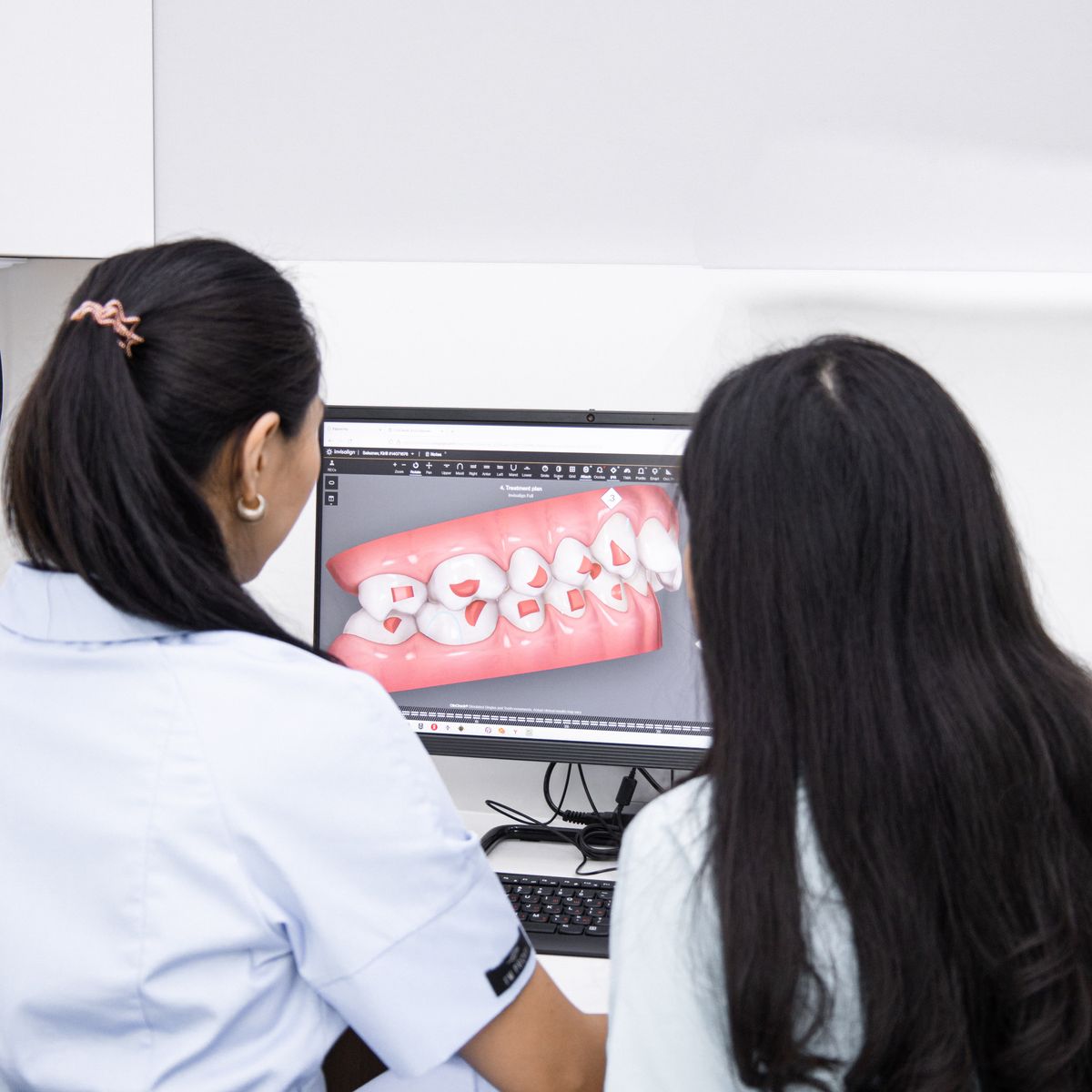 Two clinicians reviewing a digital scan of the teeth on screen