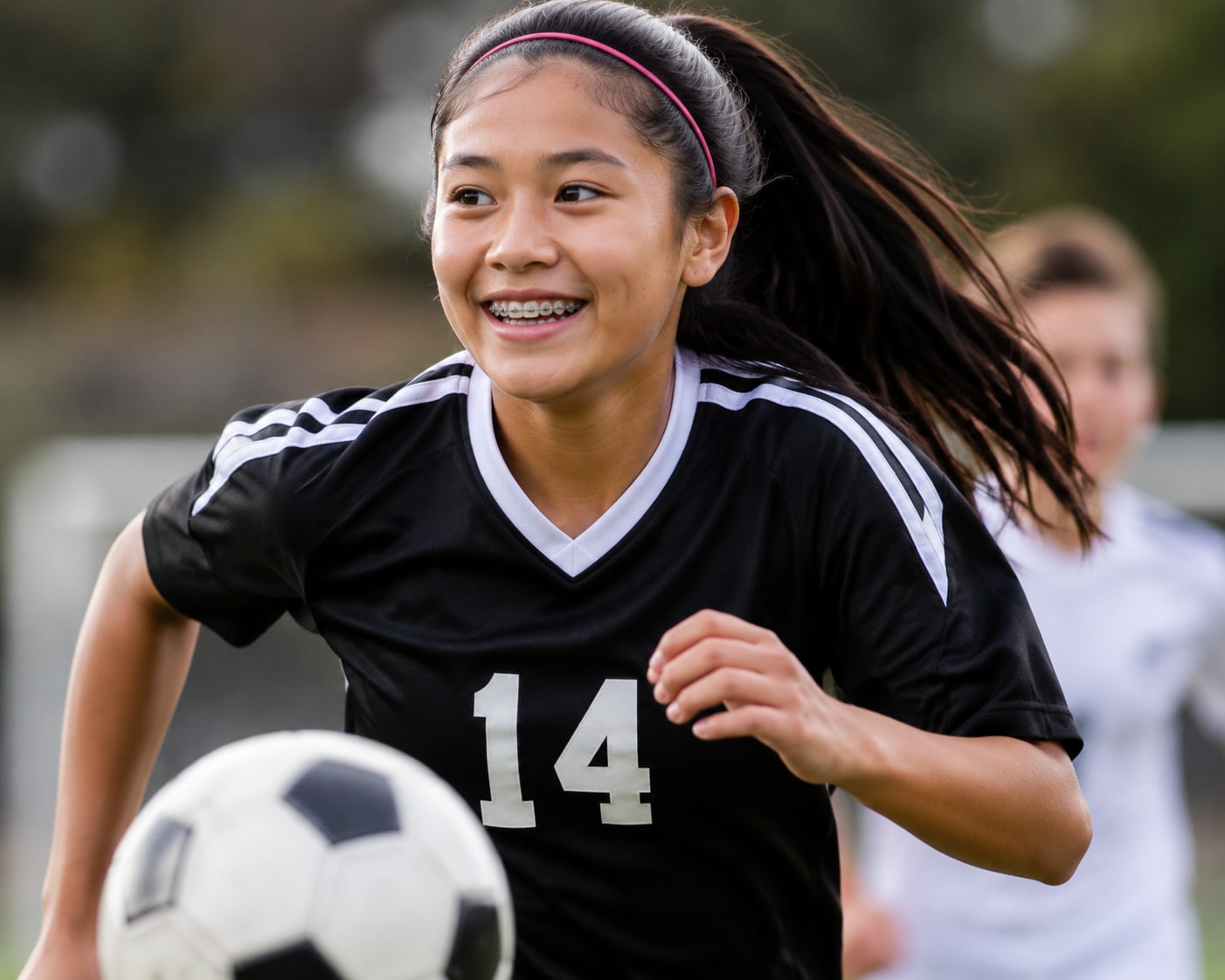 A teenager with braces smiling mid-game on a soccer field